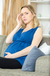 © auremar - pregnant woman sat on the sofa suffering with a headache
