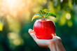 Red apple close up in hand on green natural blurred background, copy space