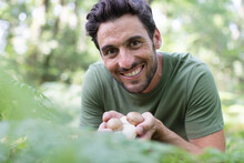 cheerful man gathering mushrooms in the woods