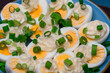Przekrojone na pół jajka na twardo z majonezem i szczypiorkiem leżą na talerzu, z bliska