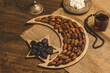 Dried dates on a tray in the shape of a month and a star with tea and sugar cubes on a wooden background with burlap. Ramadan Kareem holiday background.  Soft focus. Shallow DOF.