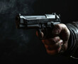 Close up of a man holding a gun in his hand against black background