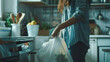 Woman taking garbage bag out of trash bin in kitchen, closeup.