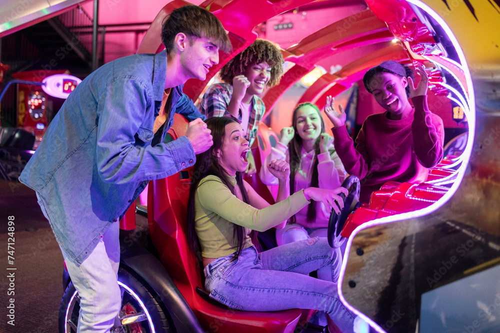 group of multiracial friends having fun playing video arcade and ...