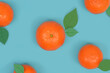 Tangerines with leaves on blue background, phot mixed with graphics, top view, texture.