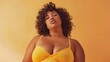 © iuricazac - A woman with curly hair wearing a yellow top posing against a warm-toned background.