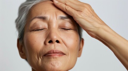 Wall Mural - A serene elderly woman with closed eyes her head gently cradled by a hand evoking a sense of peace and tranquility.