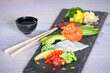 Sashimi (salmon fillet, tuna fillet, cod fillet) on a tray served with soya sauce