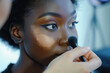 Makeup artist applies Makeup artist applies powder and blush . Beautiful African American Woman face. Hand of make-up master puts blush on cheeks beauty model girl. Make up in process .