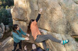 © ADDICTIVE STOCK - An eager climber reaches for the next hold while being closely spotted by teammates on a sunlit boulder