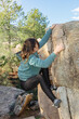 © ADDICTIVE STOCK - A determined climber uses precise hand and foot placements to ascend a challenging boulder in a forested area