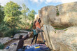 © ADDICTIVE STOCK - Climber making an energetic move on a boulder with the active guidance and spotting of a friend, surrounded by nature.