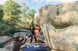 © ADDICTIVE STOCK - A climber stretches to grasp a hold on a rock face, while friends provide support and spotting on a sunny day.