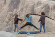 © ADDICTIVE STOCK - A climber executes a dynamic move on a boulder while two friends provide careful spotting and support
