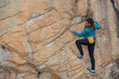 © ADDICTIVE STOCK - A focused female climber with a chalk bag strategically maneuvers on a steep boulder face during an outdoor climb