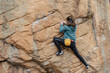 © ADDICTIVE STOCK - A focused female climber with a chalk bag strategically maneuvers on a steep boulder face during an outdoor climb