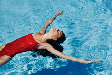 Wall Mural - Happy woman swimming in pool in red swimsuit with loose long hair, skin protection with sunscreen, concept of relaxing on vacation.