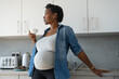 Pregnant woman holding tea cup in kitchen