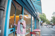 Young woman in hijab using phone while entering cafe