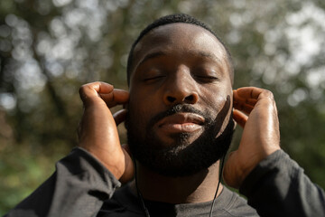 Wall Mural - Close-up of man with earbuds standing in park