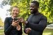 © Cultura Creative - Smiling athletic man and woman looking at smart phone in park