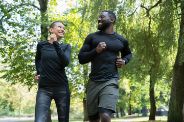 Wall Mural - Smiling man and woman jogging in park