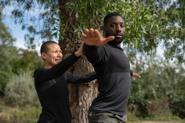 Wall Mural - Yoga instructor assisting man practicing yoga in park