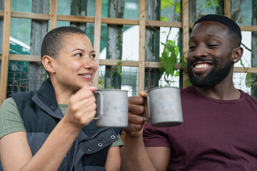 Wall Mural - Smiling couple with metal mugs relaxing in urban garden