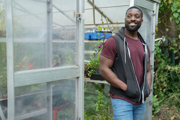 Wall Mural - Portrait of smiling man standing in front of greenhouse