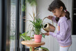 Little girl watering plant at home