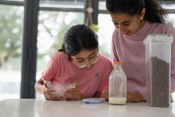 Wall Mural - Mother and daughter using phone during breakfast