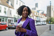 Portrait of smiling woman standing with disposable cup on sidewalk