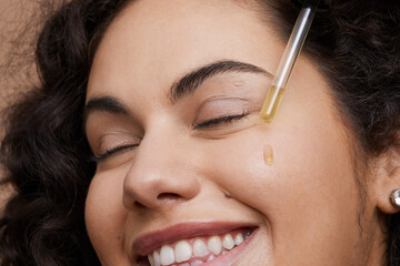 Close-up of young woman applying face serum