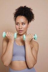 Wall Mural - Studio portrait of woman exercising with dumbbells