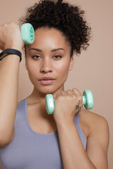 Wall Mural - Studio portrait of woman exercising with dumbbells