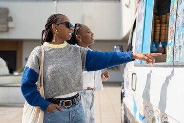 Wall Mural - Young female friends buying ice cream in ice cream truck