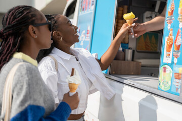 Wall Mural - Young female friends buying ice cream in ice cream truck