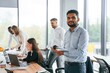 © standret - Indian man is standing in front of colleagues that are using laptop. Group of office workers are together indoors