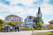 View Of The Ancient Wooden Gothic-type City Hall With Turrets, Spire On A Sunny Day Against A Background Of Blue Sky With Clouds, Guyana. World Tourism, Architecture.