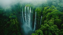 This Is A Stunning Aerial View Of A Waterfall In The Middle Of A Lush Green Forest.