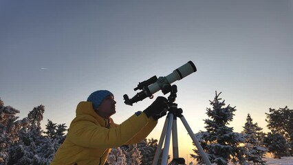 Wall Mural - amateur astronomer looking at the skies with a telescope in winter time.