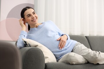 Canvas Print - Happy pregnant woman on sofa at home