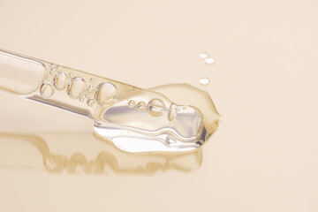 Wall Mural - Pipette with serum, gel, oil or other cosmetic product on a beige background. macro