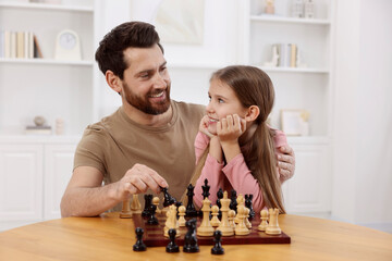 Wall Mural - Father teaching his daughter to play chess at home