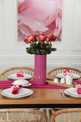 Canvas Print - Color accent table setting. Plates, cutlery, pink napkins and vase with beautiful roses in dining room