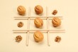 Tic tac toe game made with walnuts and cookies on beige background