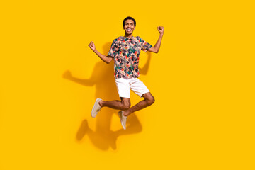 Wall Mural - Full length photo of funky lucky guy dressed print t-shirt jumping high rising fists isolated yellow color background