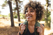 © Wavebreak Media - A young biracial woman with curly hair smiles while hiking in a forest