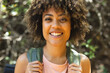 © Wavebreak Media - Young biracial woman smiles brightly, standing outdoors with greenery in the background on a hike