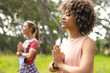 © Wavebreak Media - Young biracial woman with curly hair meditates in a park, hands pressed together